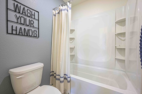 Interior photo of guest bathroom with shower, toilet, and wall decor