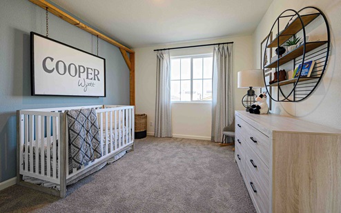 Interior photo of bedroom with crib, dresser, and large window.