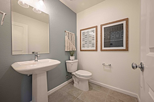 Interior photo of guest bathroom with sink, toilet, and large mirror