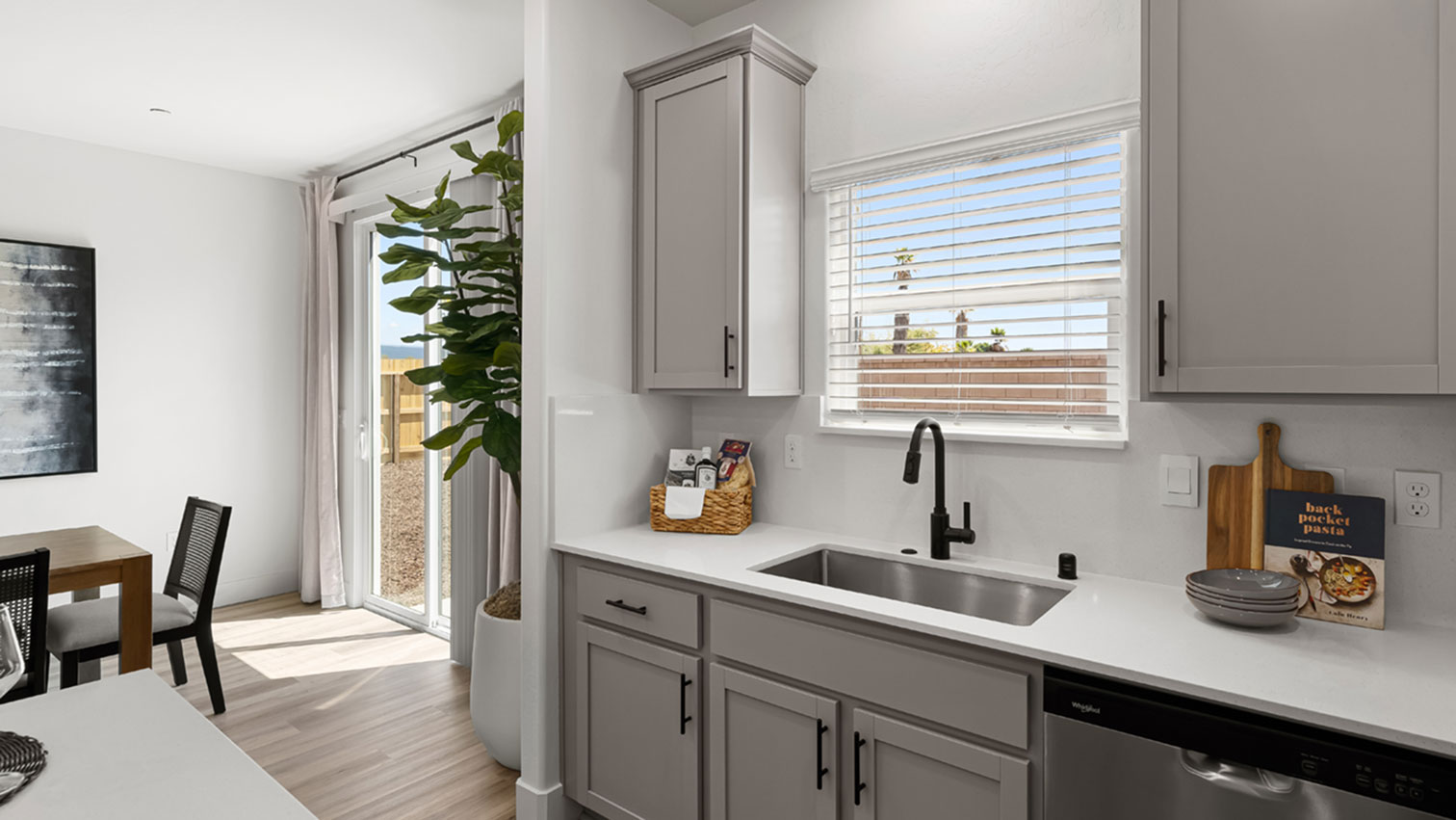 Kitchen with sink and dark faucet beneath a window, cabinetry, and expansive flooring