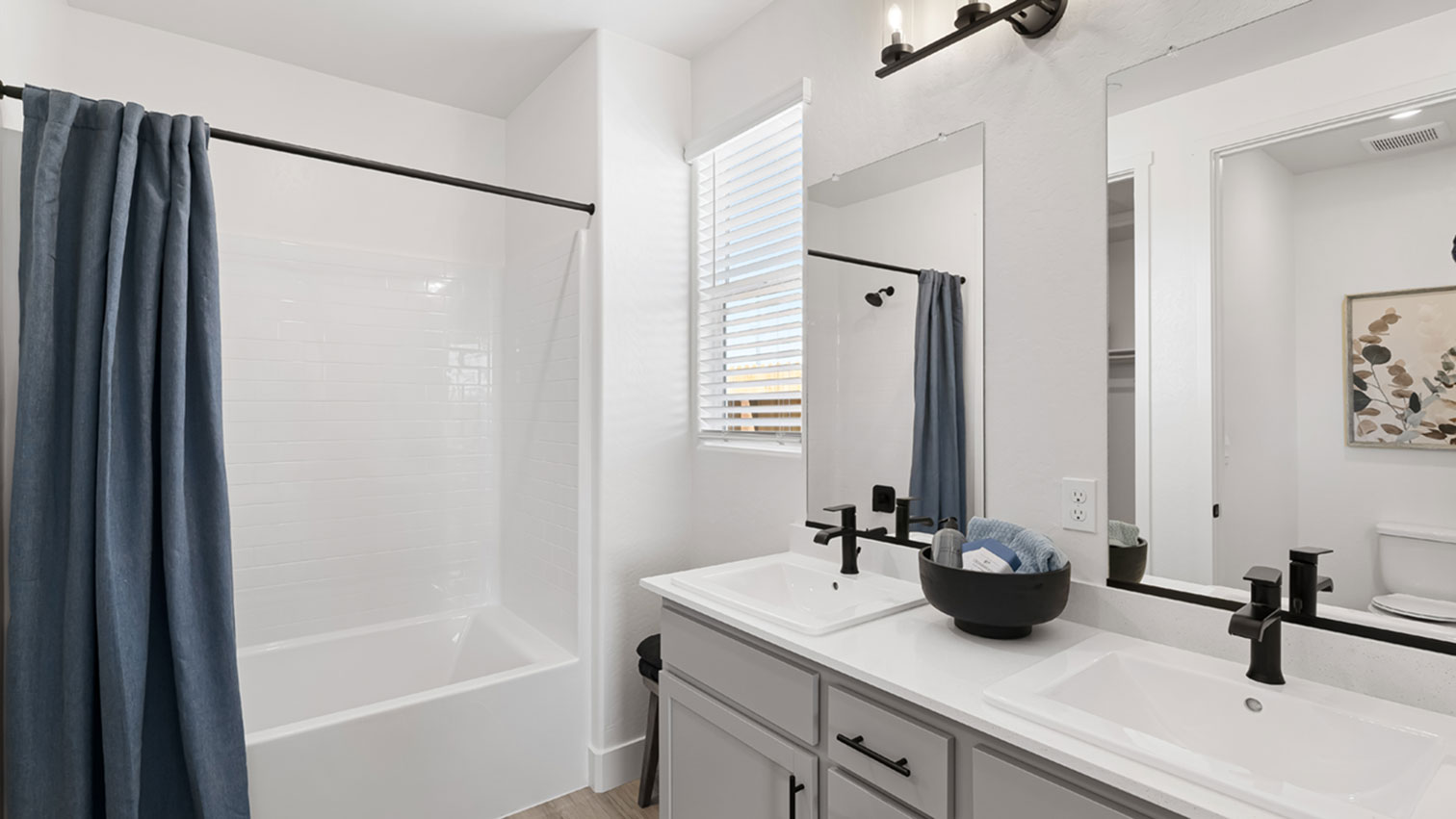 Bathroom with double vanity, mirrors, window, and walk-in shower
