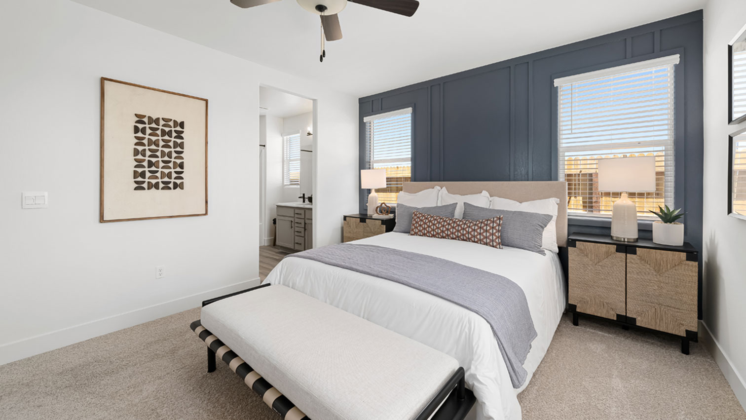 Primary bedroom with plush carpeting, ceiling fan, and direct access to bathroom