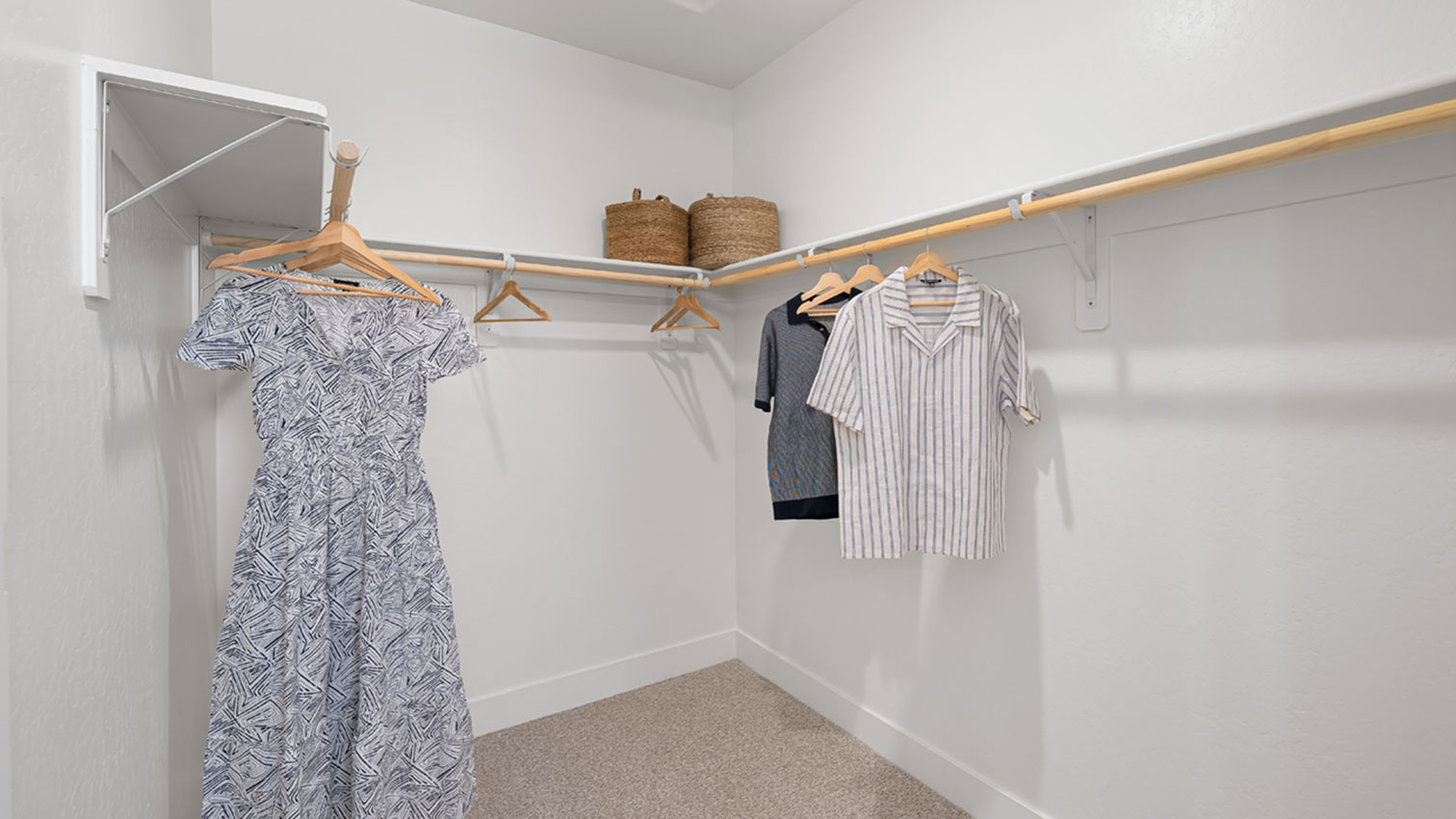 Primary walk-in closet with wraparound hanging rods, storage shelving, and plush carpeting