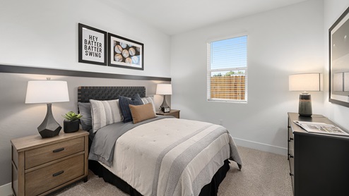 Photo of guest bedroom with full size bed, matching end tables and a large window