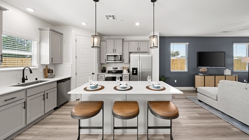 Interior photo of open concept kitchen with whit countertops, white cabinets and a large island