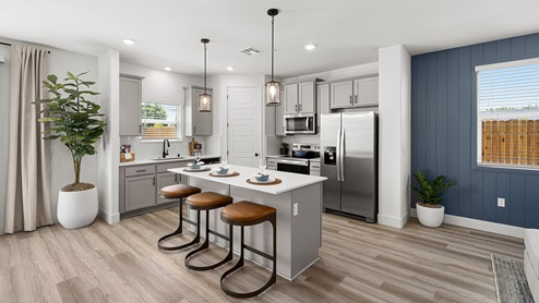 Interior photo of open concept kitchen with whit countertops, white cabinets and a large island