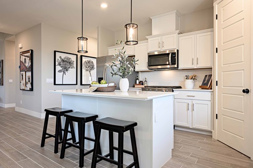 Bright kitchen with white shaker cabinets, pendant lighting, and island seating