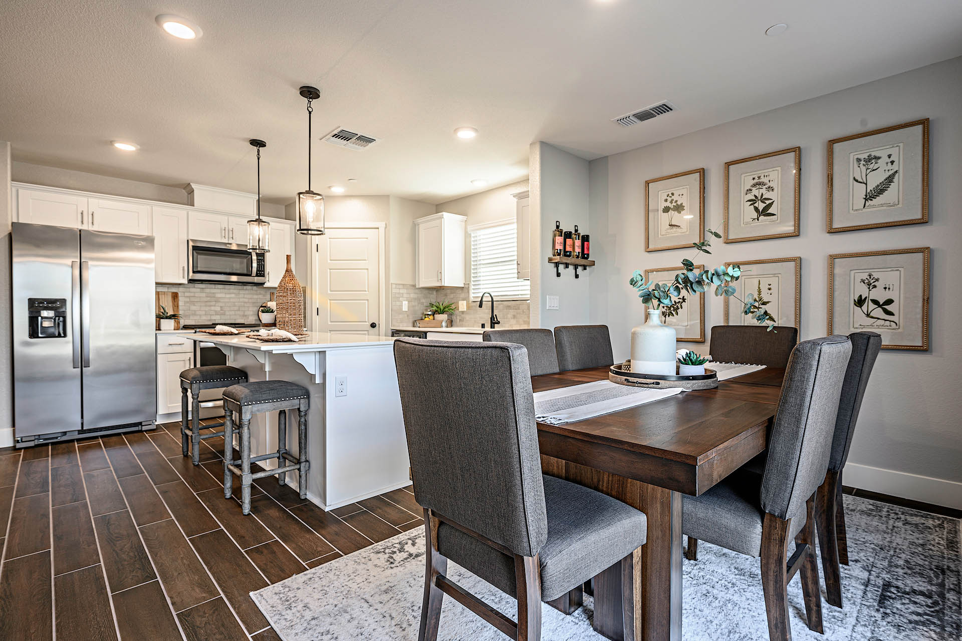 Interior photo of open concept dining room adjacent to kitchen with dining table and chairs.