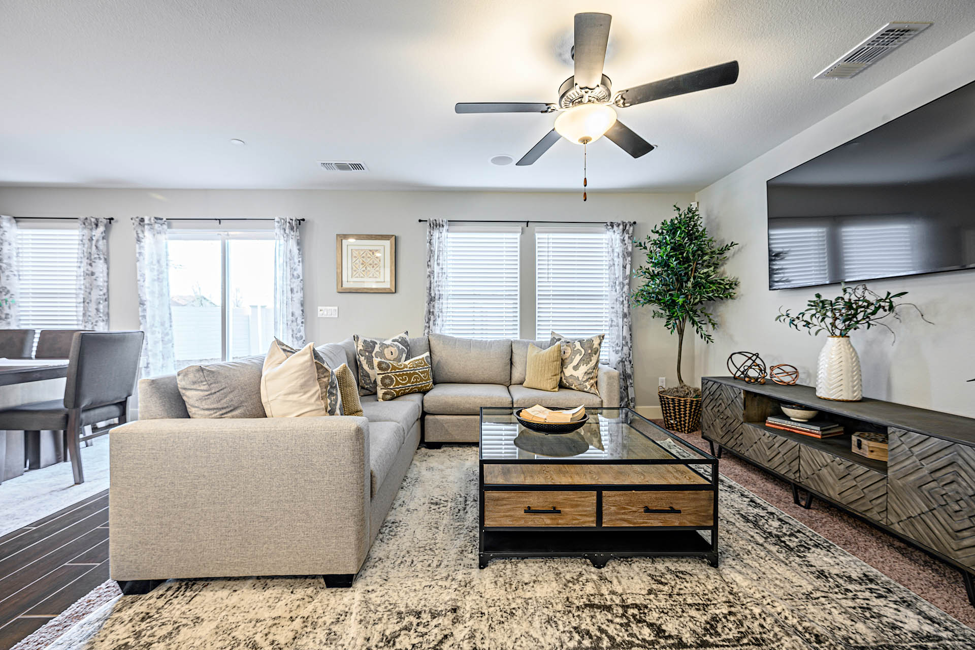 Interior photo of open concept living room with large sectional couch, large windows, and coffee table.