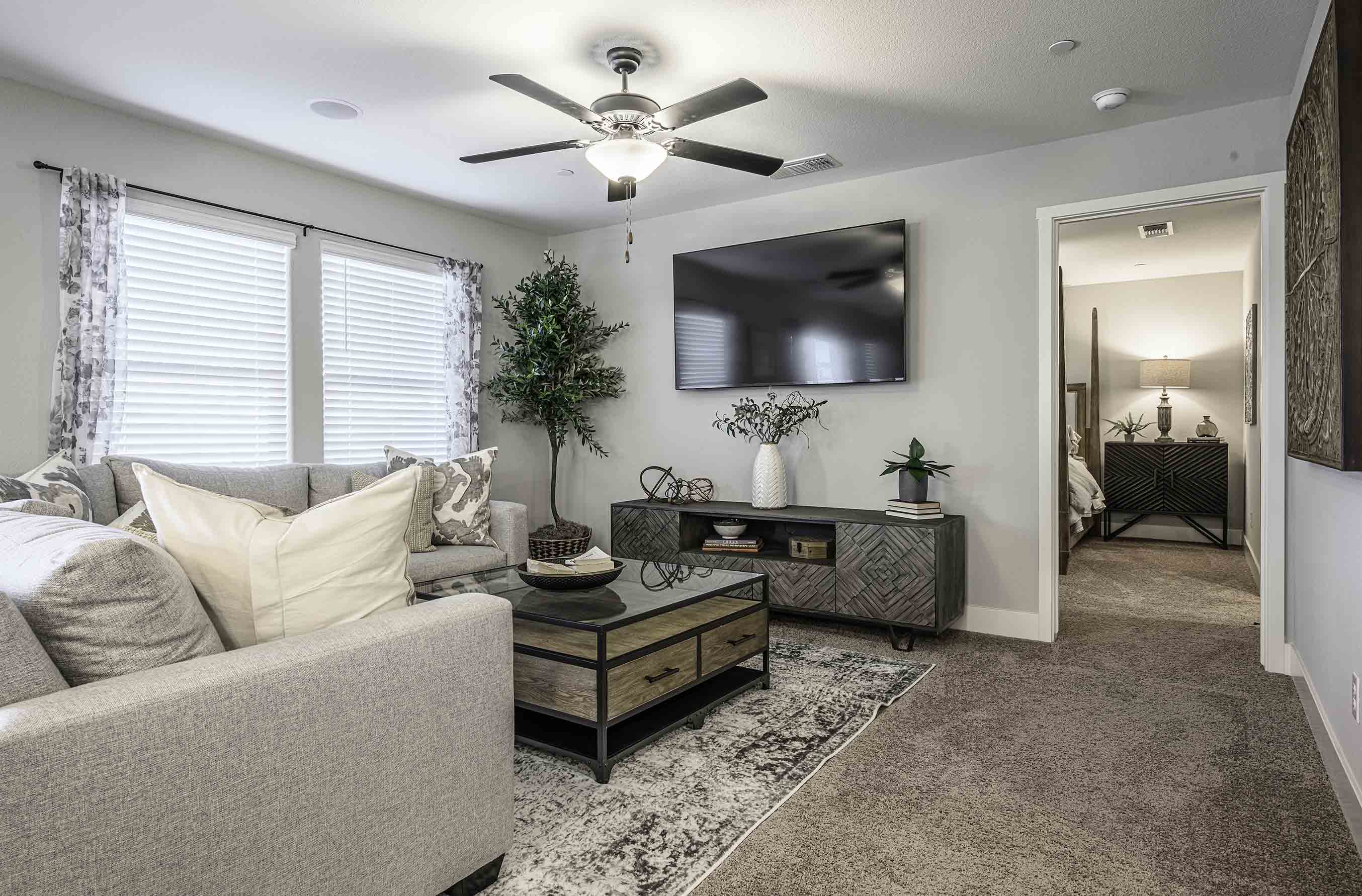 Interior photo of open concept living room with large sectional couch, large windows, TV, and coffee table.