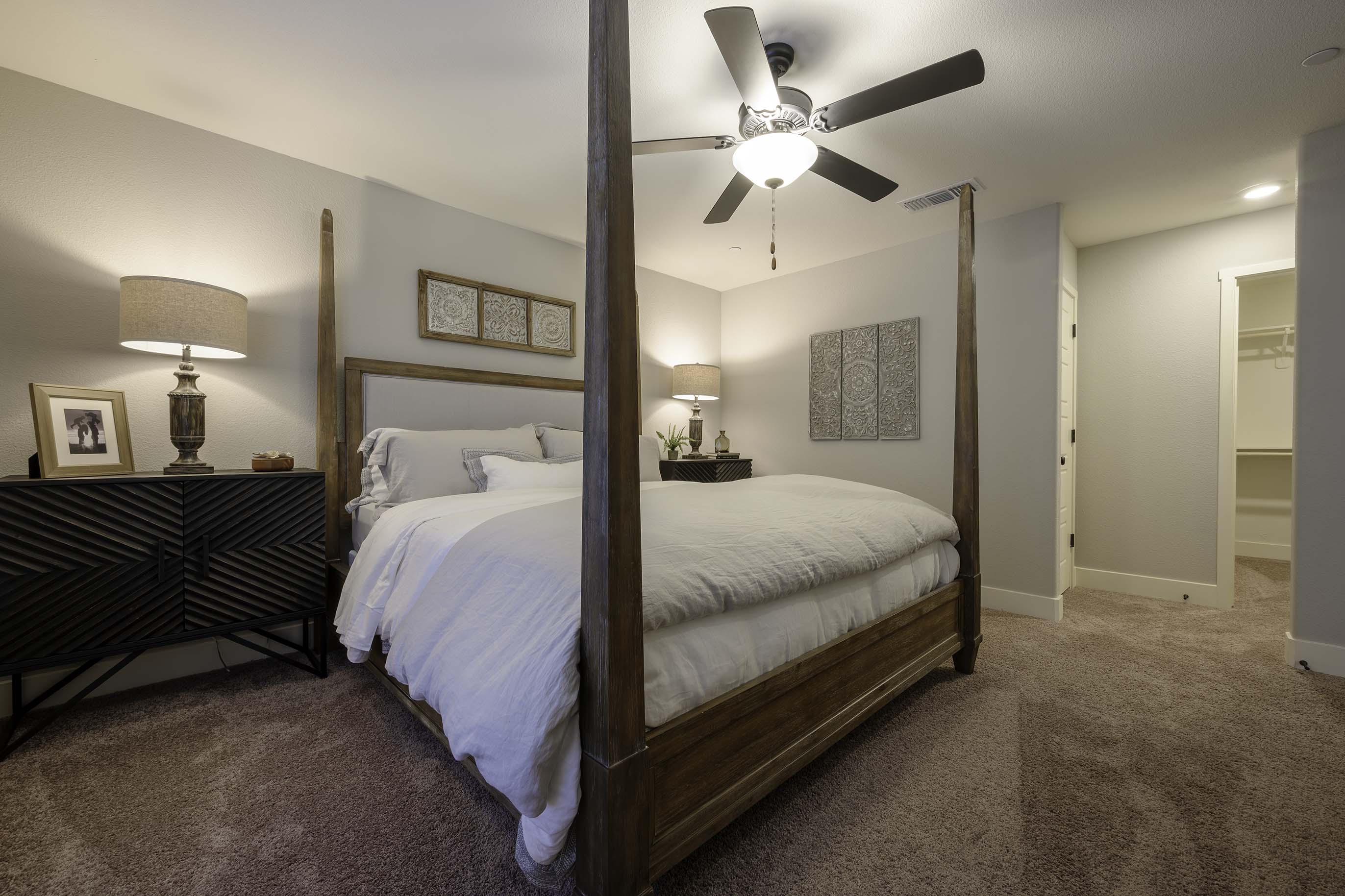 Interior photo of primary bedroom with bed, end table, and dresser.