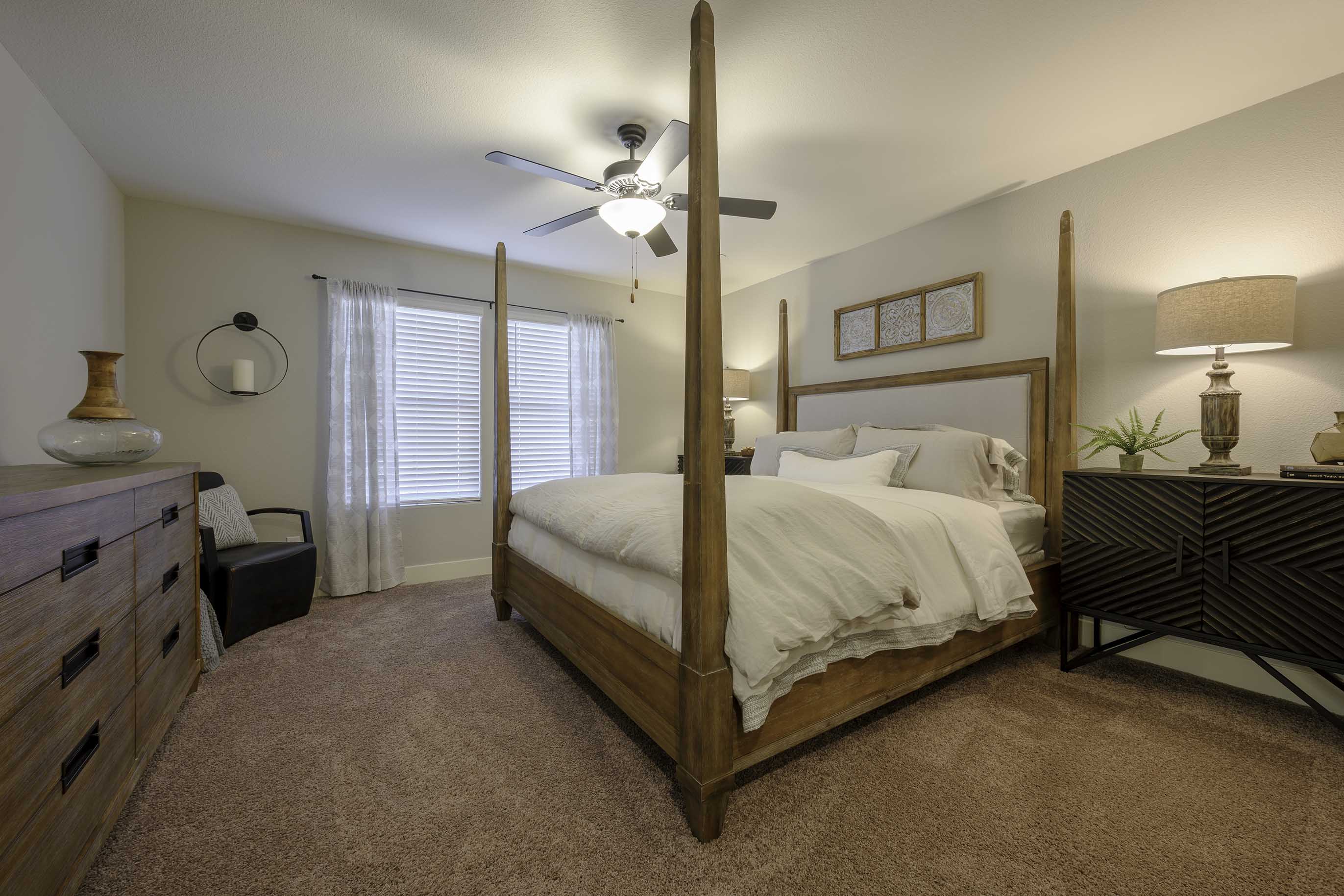 Interior photo of primary bedroom with bed, end table, and dresser.