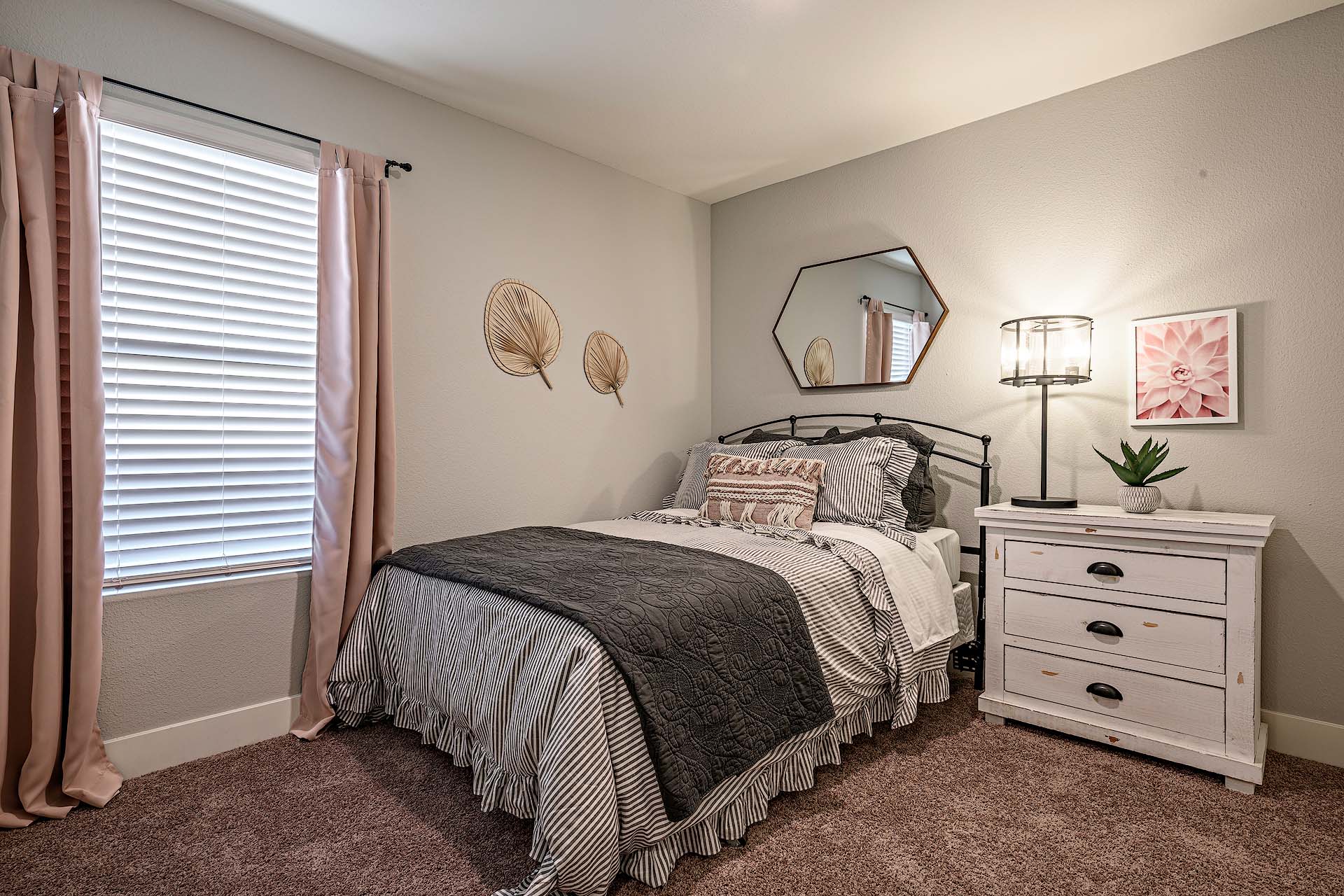 Interior photo of guest bedroom with bed, dresser, and large window.