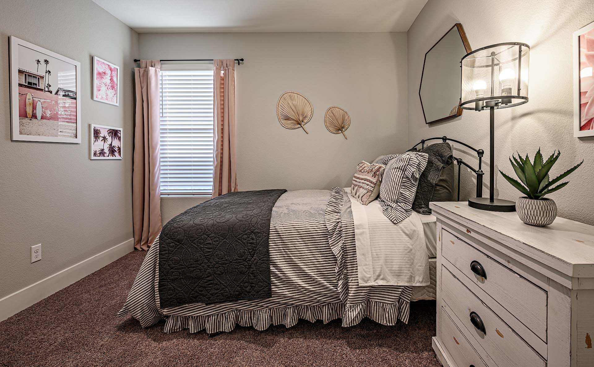Interior photo of guest bedroom with bed, dresser, and large window.