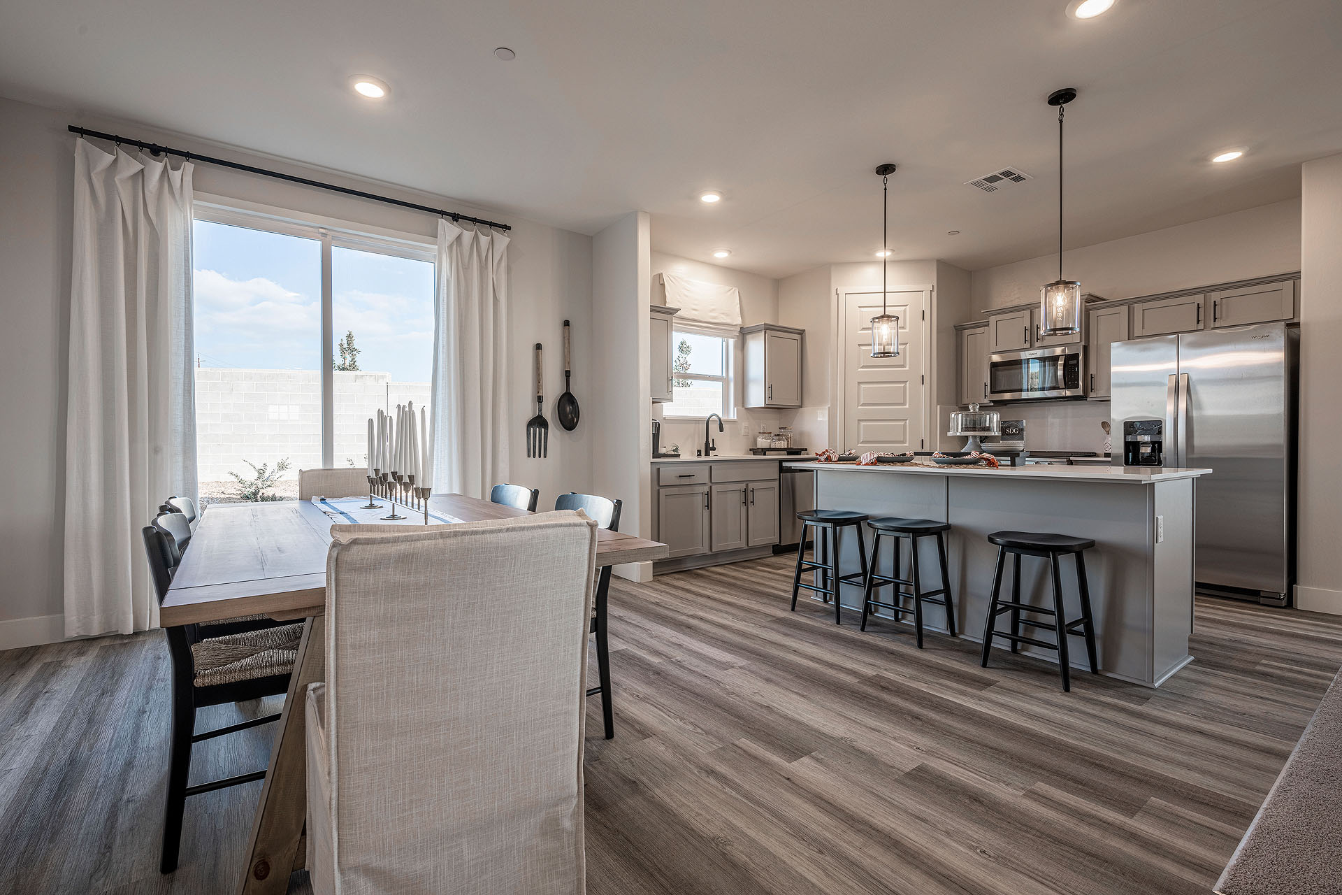 Interior photo of open concept dining room and kitchen with dining table, kitchen island, and sliding glass door to backyard.