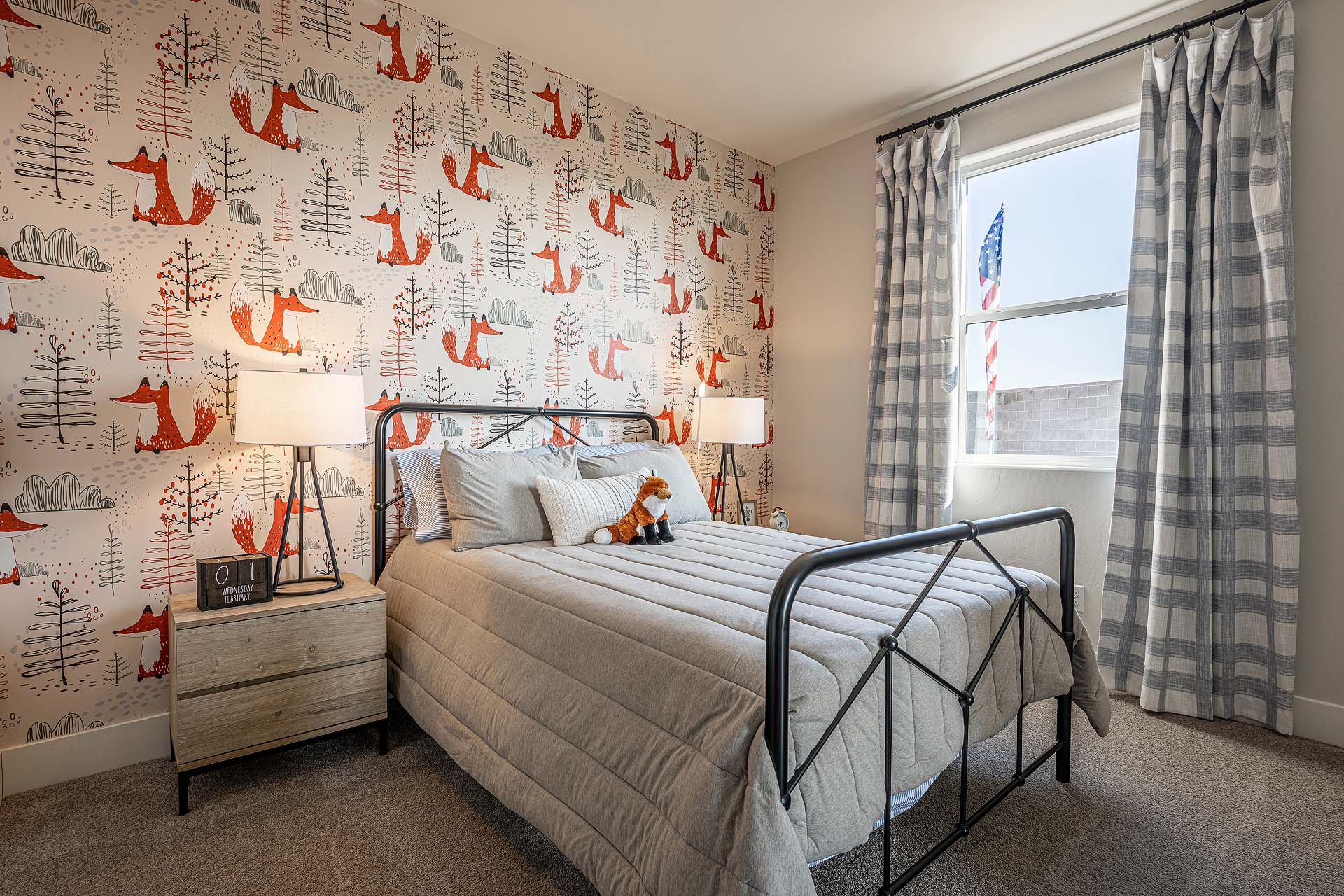 Interior photo of kid's bedroom with bed, end table, and large window.