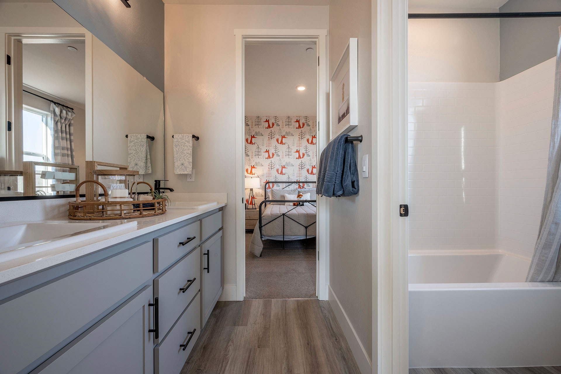 Interior photo of guest bathroom with light gray cabinets, white countertops, and shower.