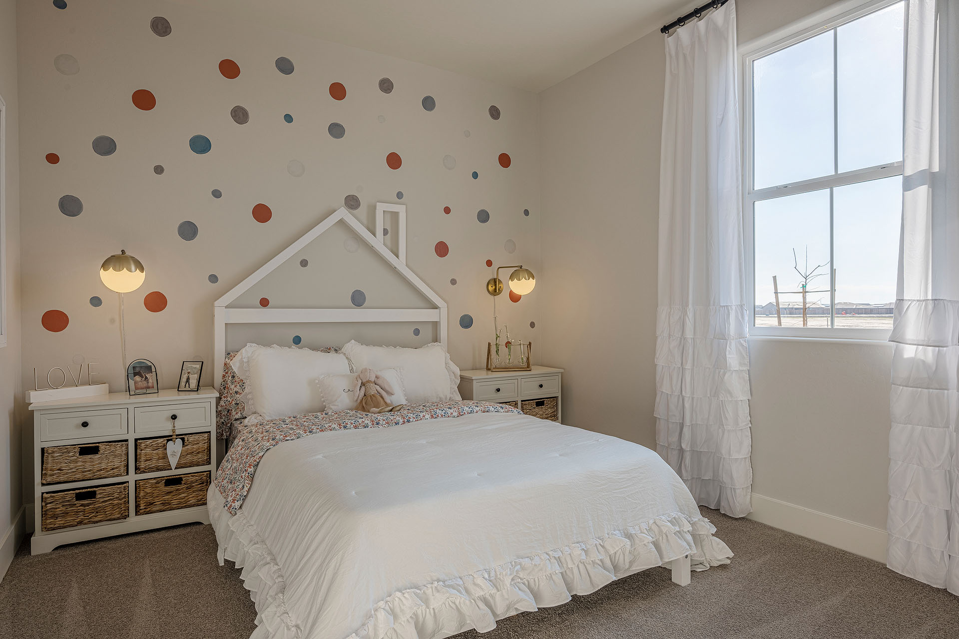 Interior photo of kid's bedroom with bed, end table, and large window.