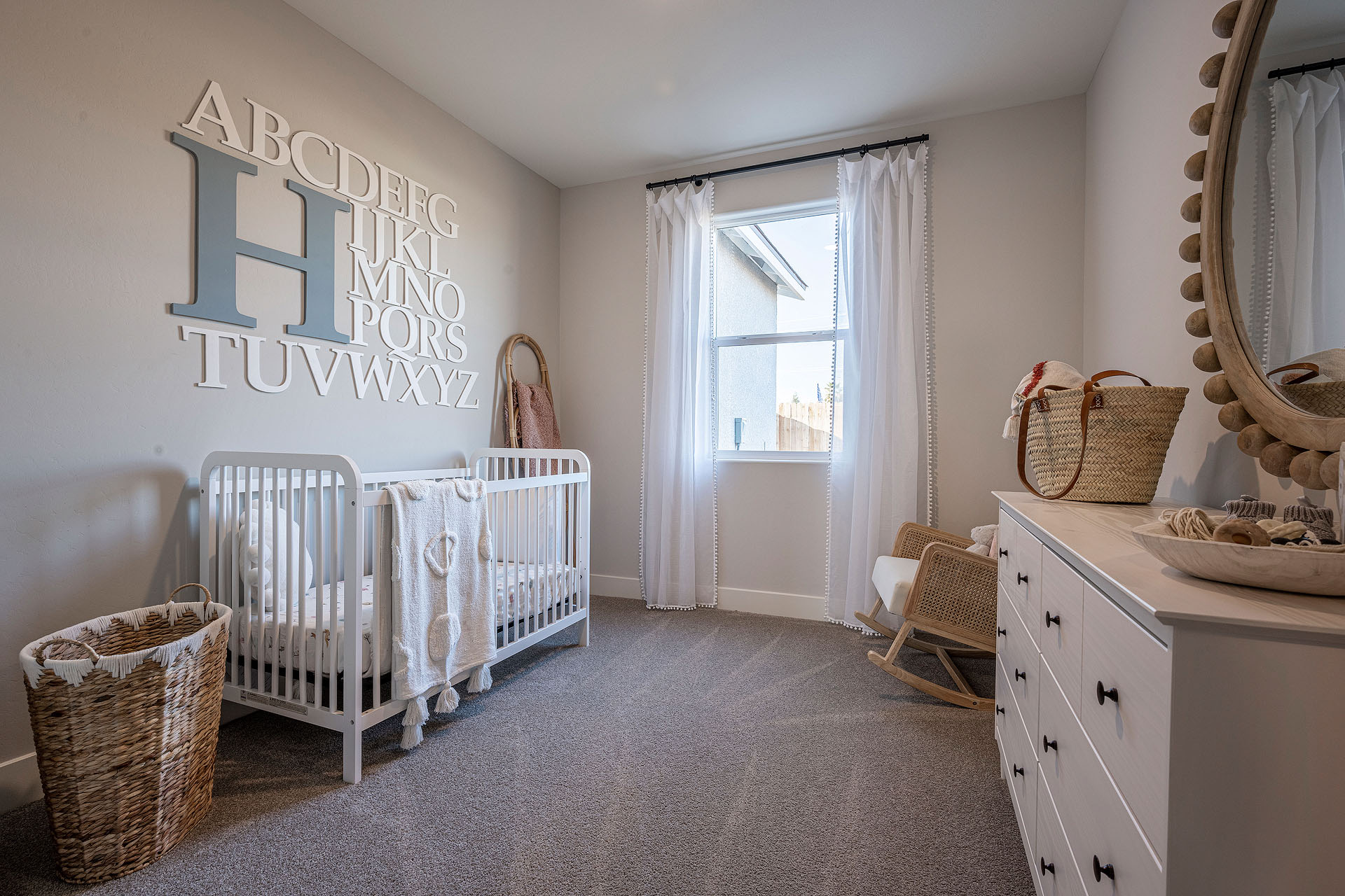 Interior photo of kid's bedroom with crib, dresser, and large window.