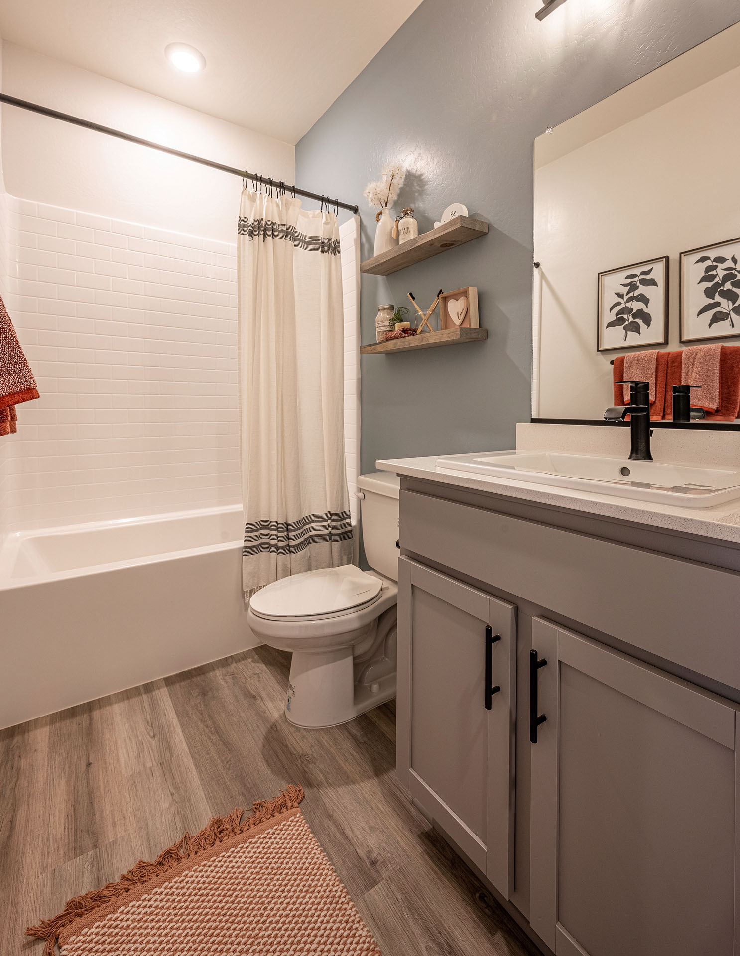 Interior photo of guest bathroom with light gray cabinets, white countertops, and shower.