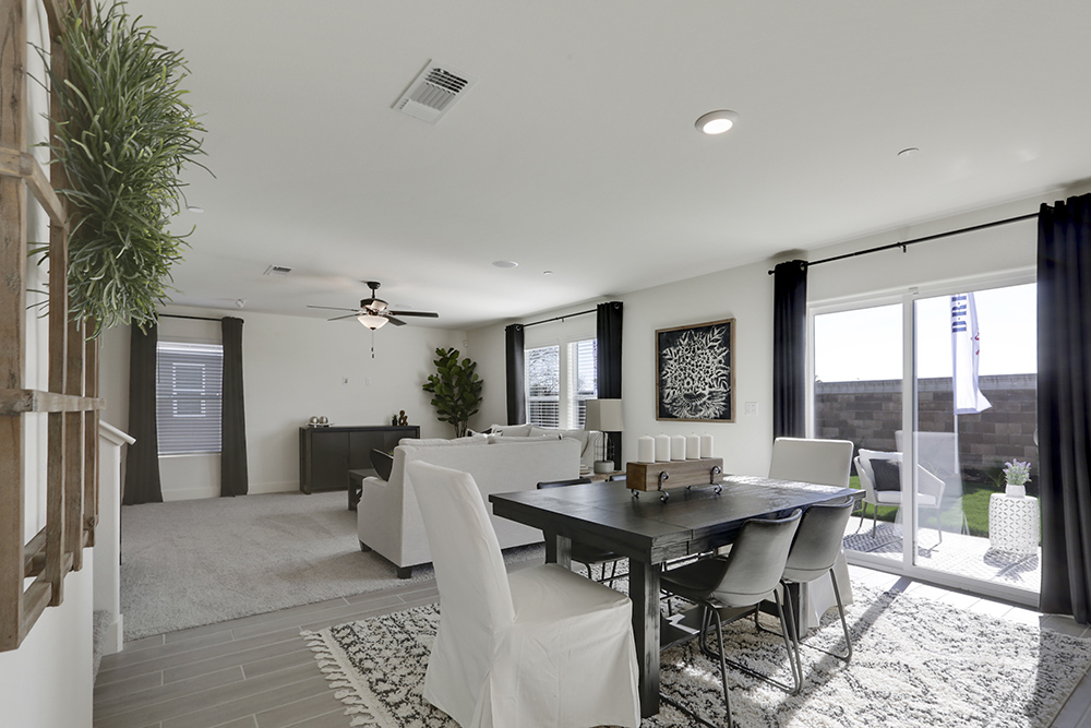 Interior photo of kitchen with white cabinets, white countertops, stainless steel appliances, and barstools at kitchen island.