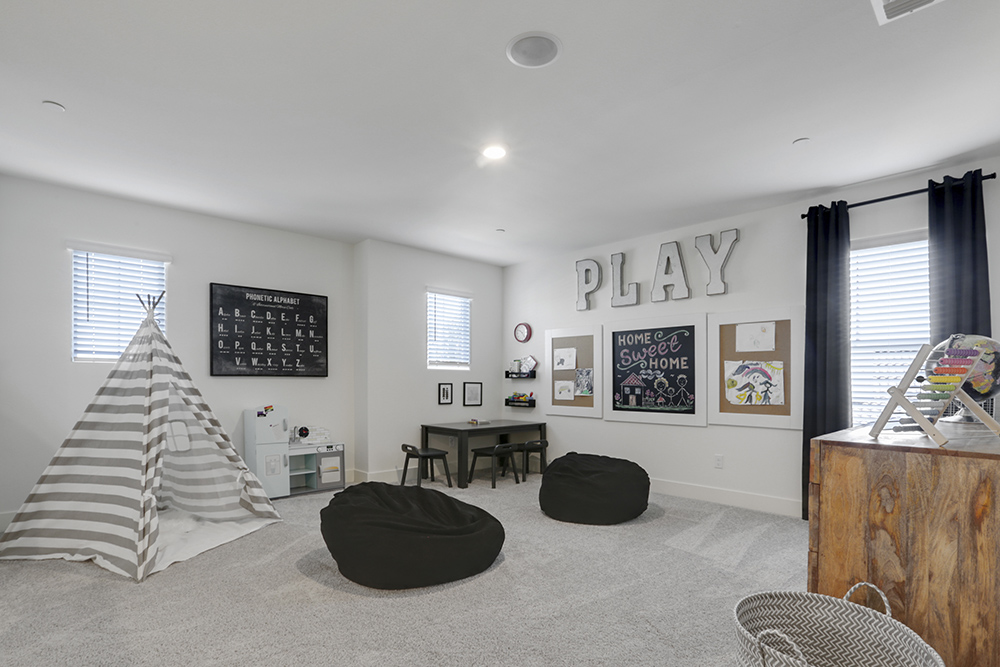Interior photo of loft with art on wall, beanbags, and large windows.