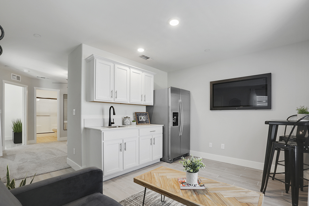 Interior photo of MultiGen kitchen with white cabinets, dining table, and stainless steel appliances.