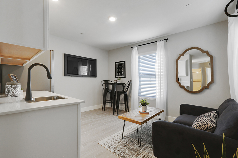 Interior photo of MultiGen kitchen with white cabinets, dining table, and stainless steel appliances.