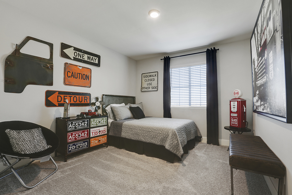 Interior photo of kid's bedroom with bed, dresser, chair, and large window.