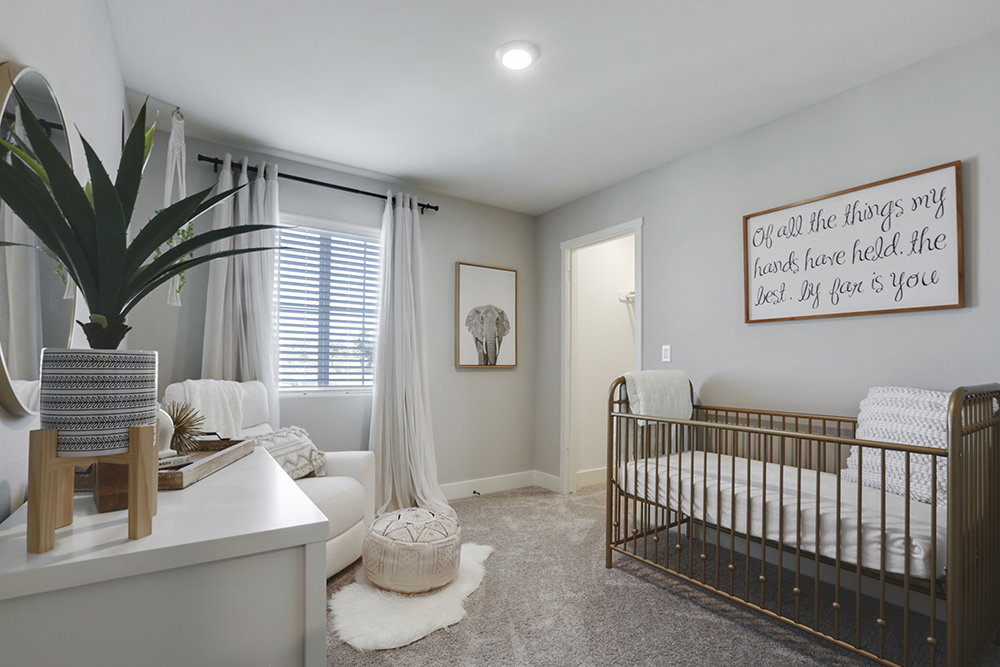 Interior photo of bedroom with crib, dresser, and large window.