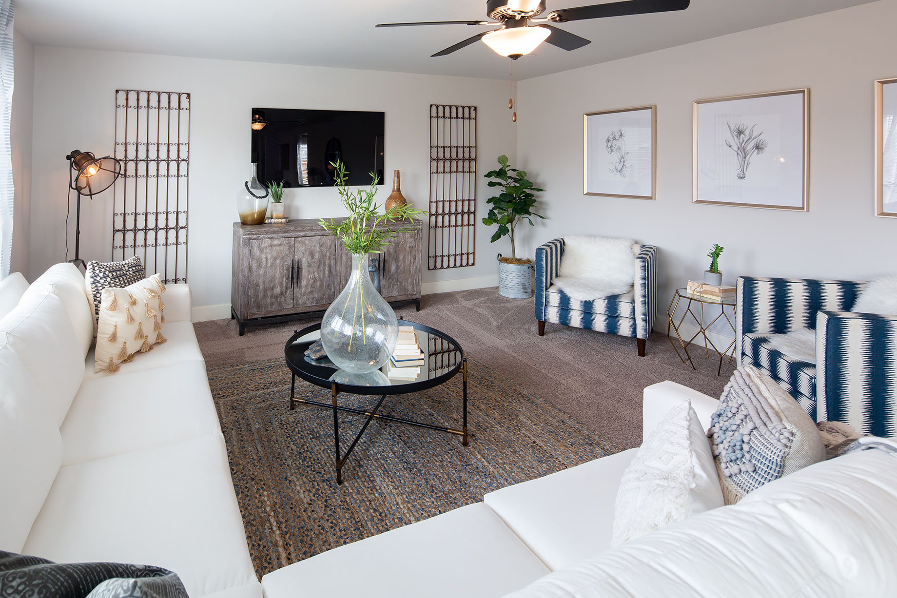 Interior photo of living room with large couch, coffee table, TV, and large windows.