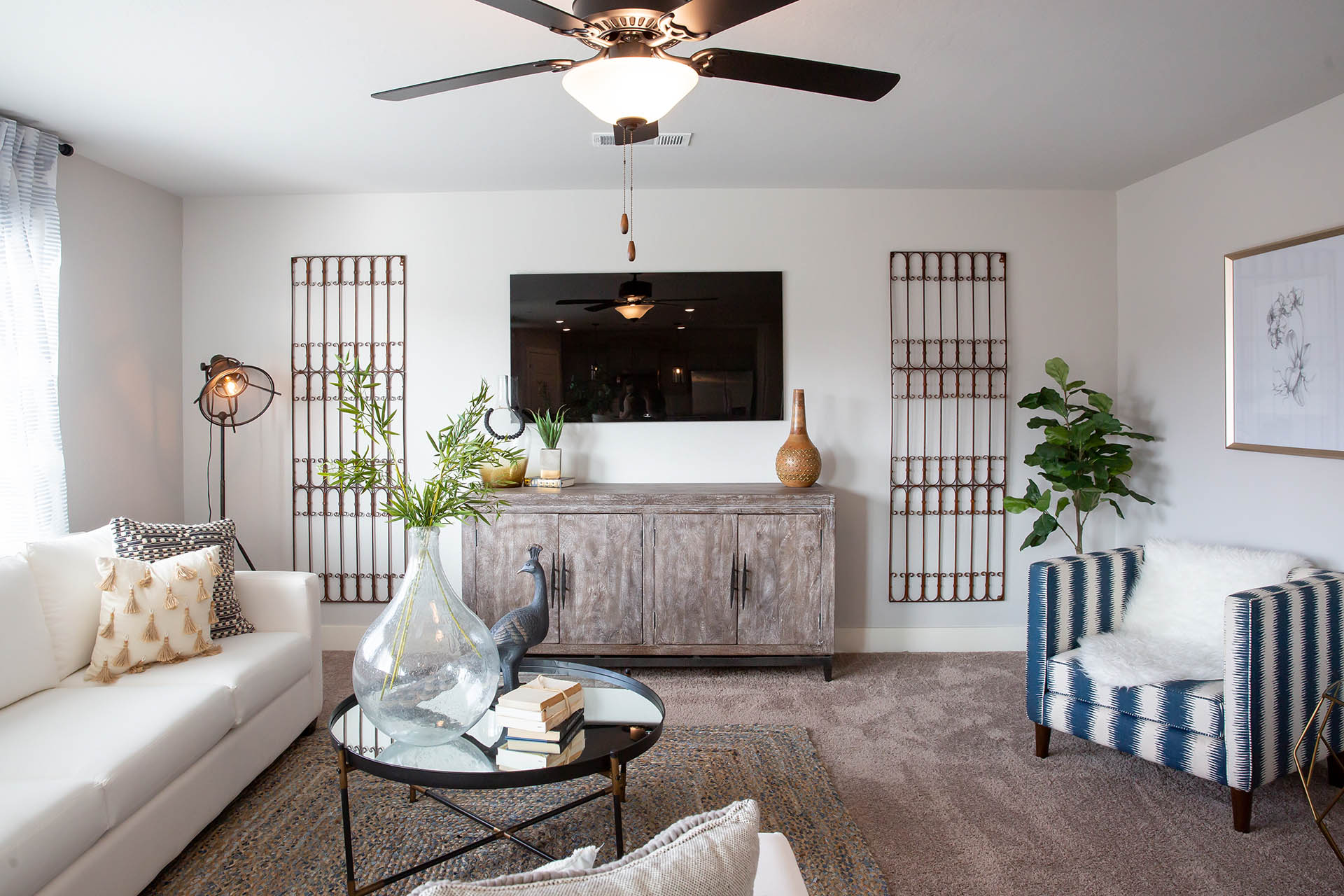 Interior photo of living room with large couch, coffee table, TV, and large windows.