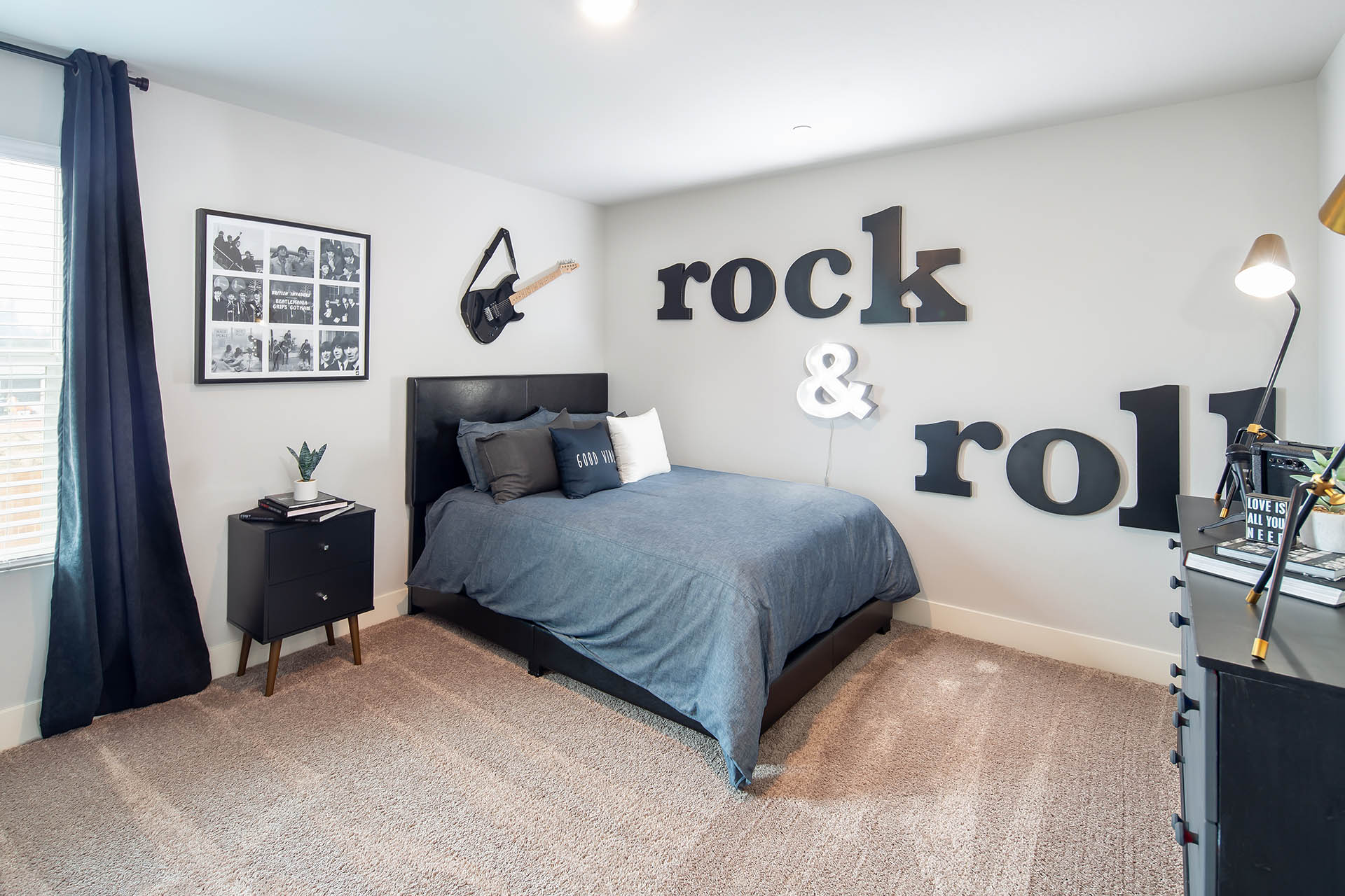Interior photo of kid's bedroom with bed, dresser, chair, and large window.