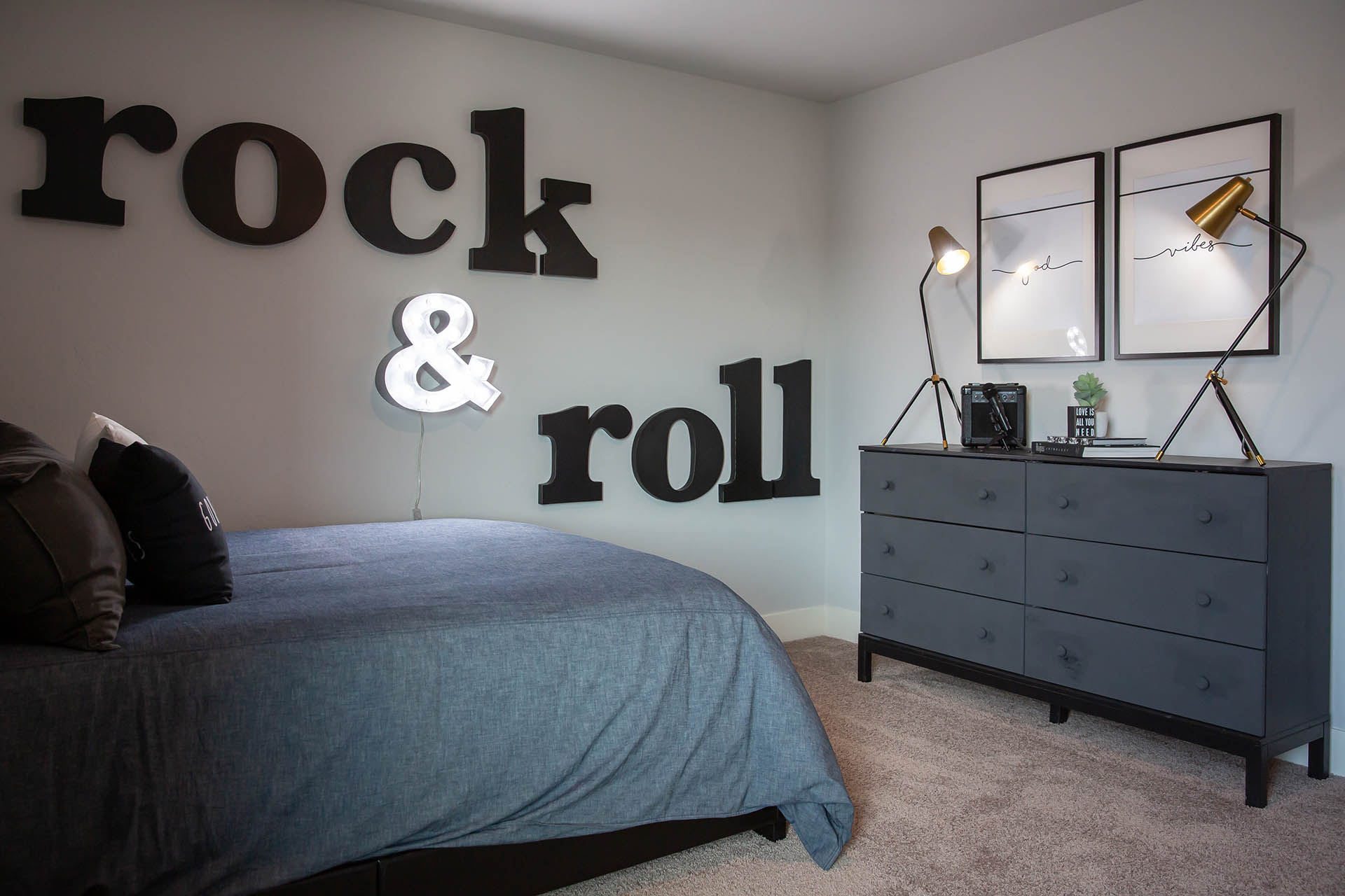 Interior photo of kid's bedroom with bed, dresser, and art on wall.