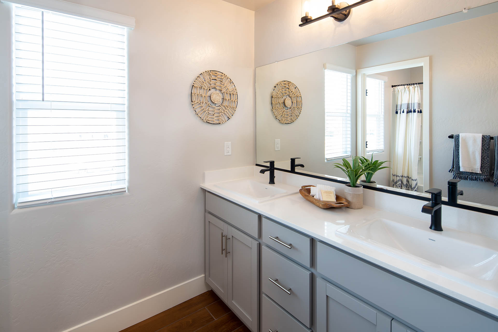 Interior photo of guest bathroom with light gray cabinets, white countertop, and window.