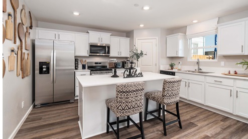 Interior photo of kitchen with large island, white countertops and white cabinets