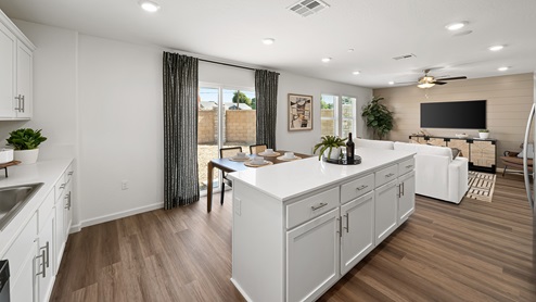 Photo of open concept kitchen with white cabinets and white countertops and an island