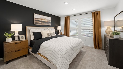 photo of primary bedroom with king size bed, black accent wall, and matching end tables