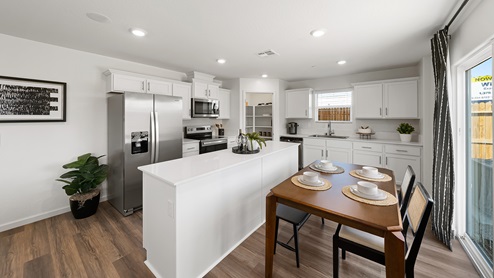 Photo of open concept kitchen with white cabinets and white countertops and an island