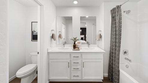 Photo of primary bathroom with dual vanity sinks, white countertops and white cabinets