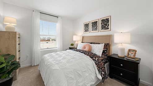 Photo of guest bedroom with full size bed, matching end tables and large window
