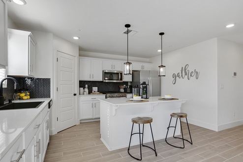 Kitchen with white cabinets, pendant lighting, and island seating