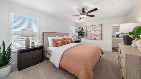 Photo of primary bedroom with king size bed, matching end tables and large windows