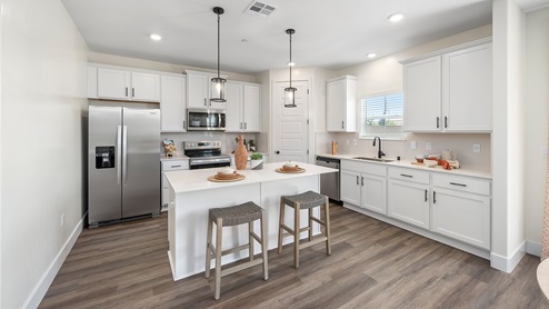 Photo of open concept kitchen with white cabinets, white countertops, and a large island