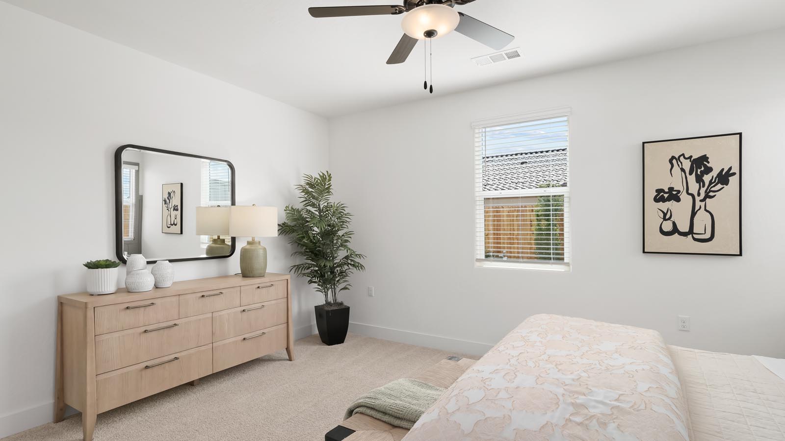 primary bedroom with dresser and plant