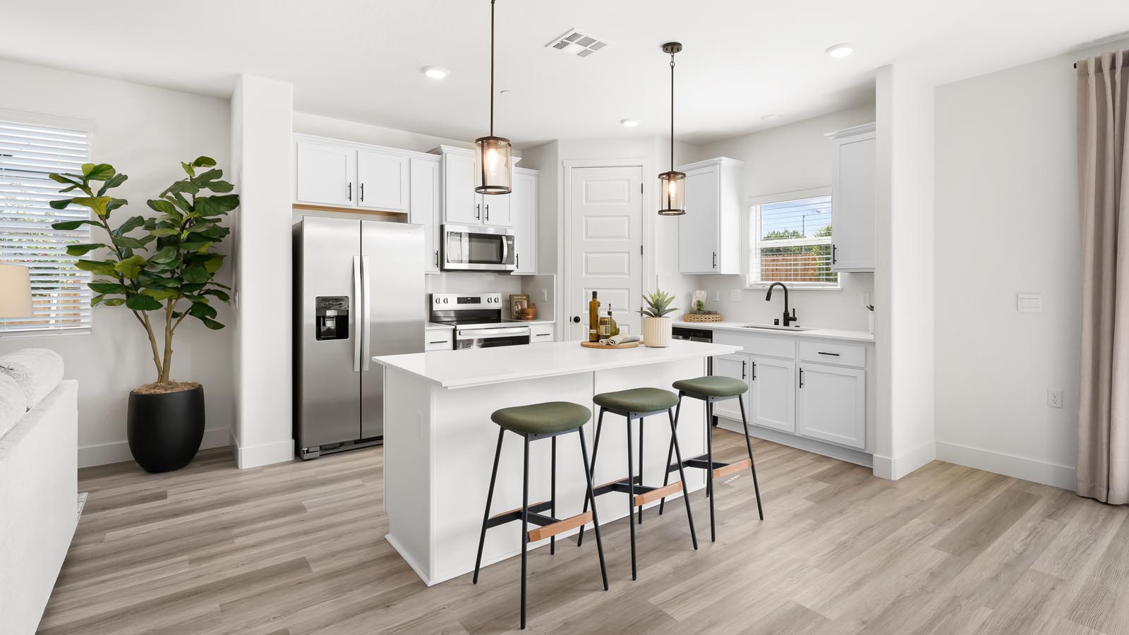 Interior photo of open concept kitchen with an island, white cabinets, white countertops, and stainless steel appliances
