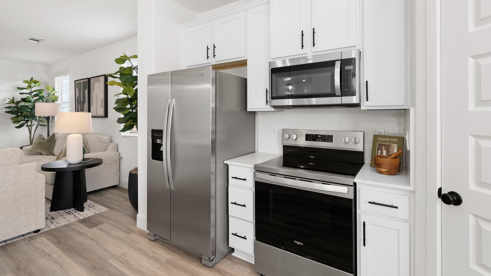Interior photo of open concept kitchen with an island, white cabinets, white countertops, and stainless steel appliances