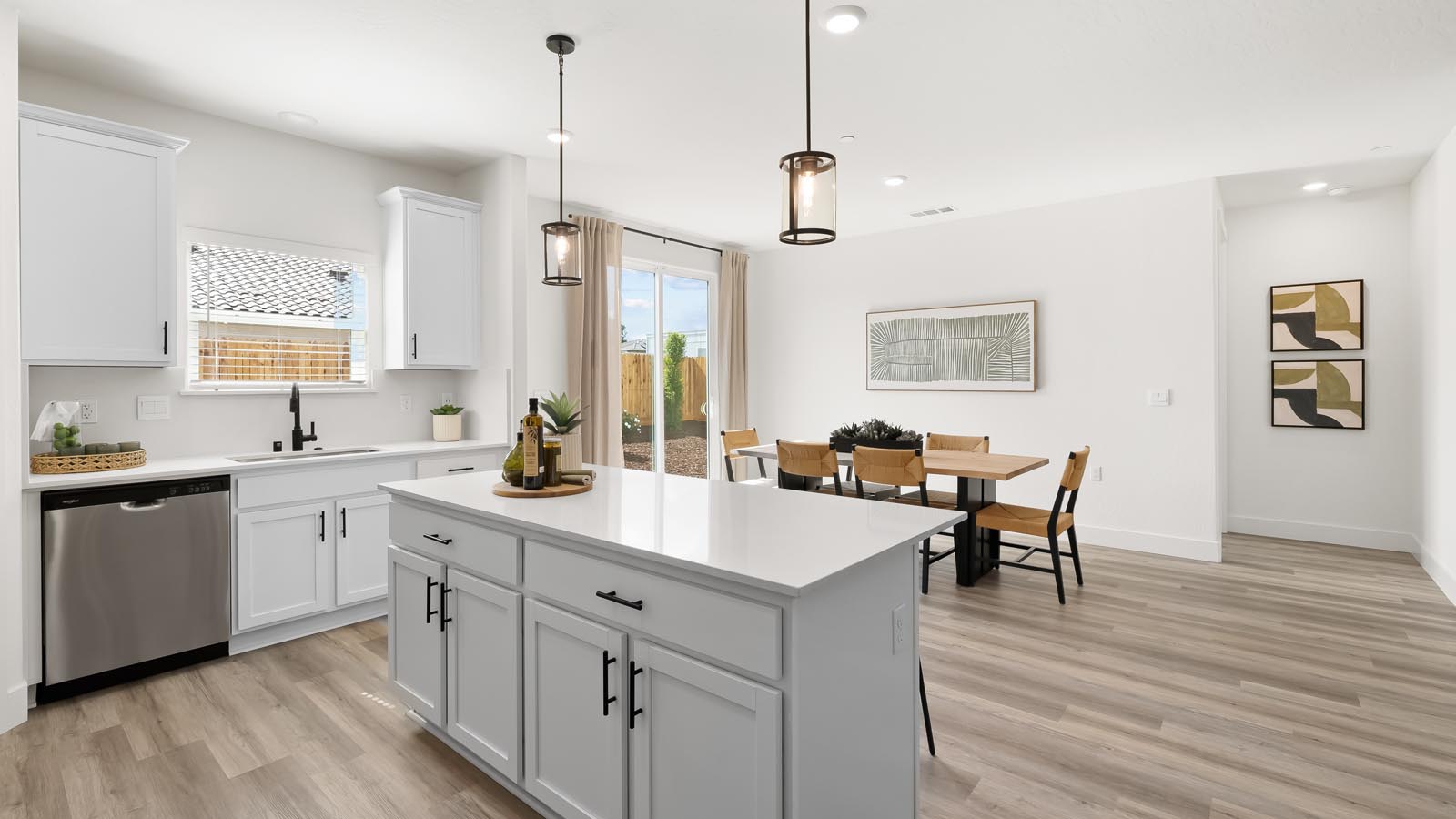 Interior photo of open concept kitchen with an island, white cabinets, white countertops, and stainless steel appliances