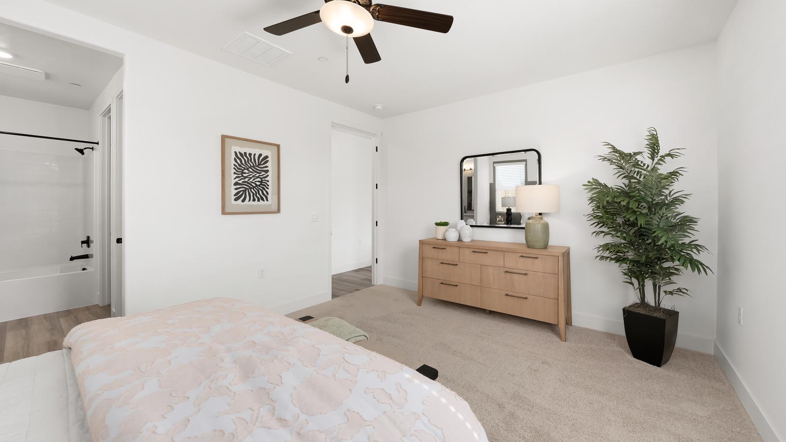 Interior photo of primary bedroom with king size bed, wooden dresser, and large windows