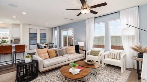 Image of open-concept living room with large windows, a couch, chairs and coffee table